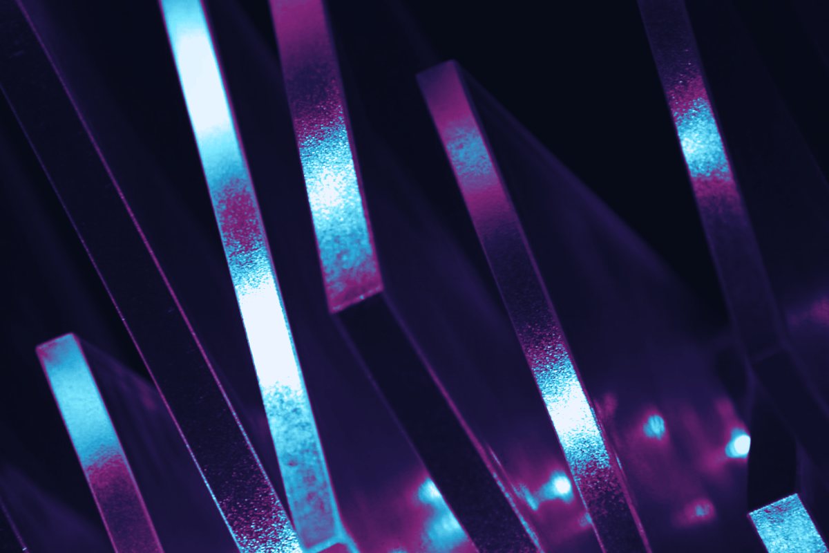 Narrow slanted blades of glass lit cyan and magenta against black